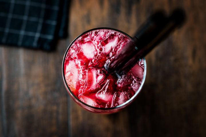 Alabama Slammer cocktail recipe garnished with two straws and served on a wooden board.