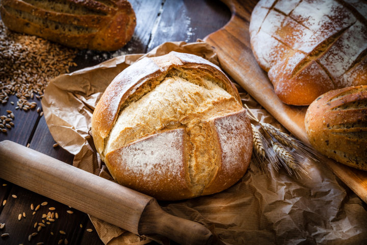 Frisch gebackenes Weizenbrot und weitere Brote auf dunklem Hintergrund