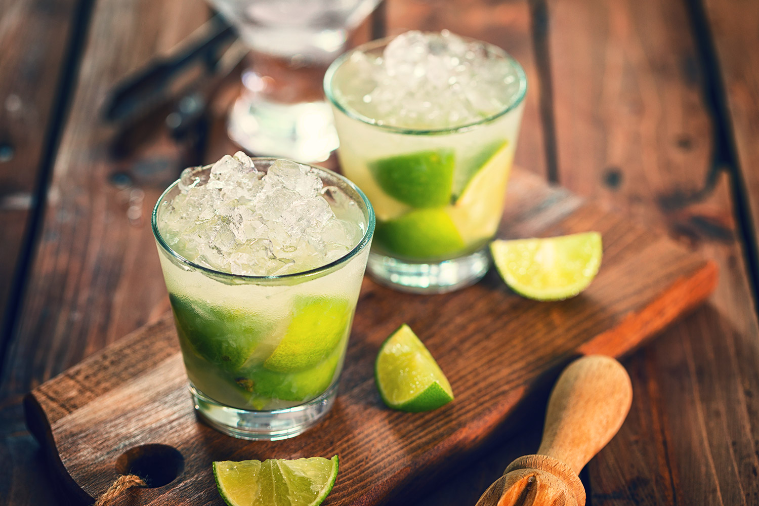 Caipirinha cocktails with lime slices on a wooden board