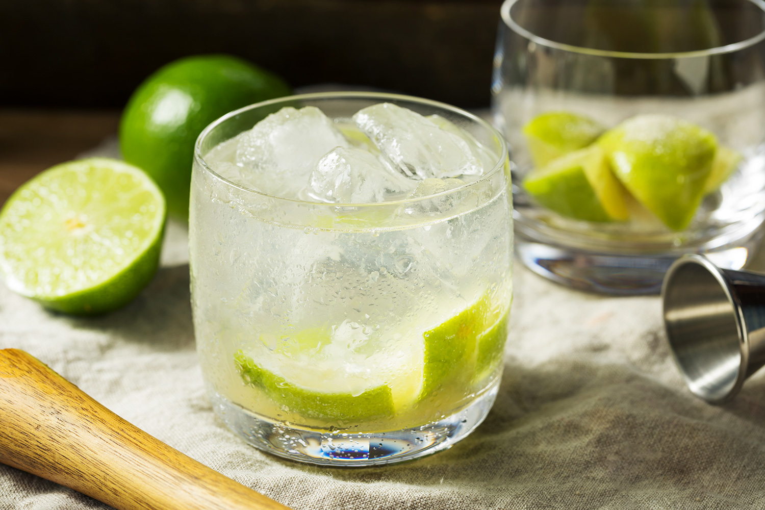 Caipiroska cocktails with limes and a pestle on a linen cloth