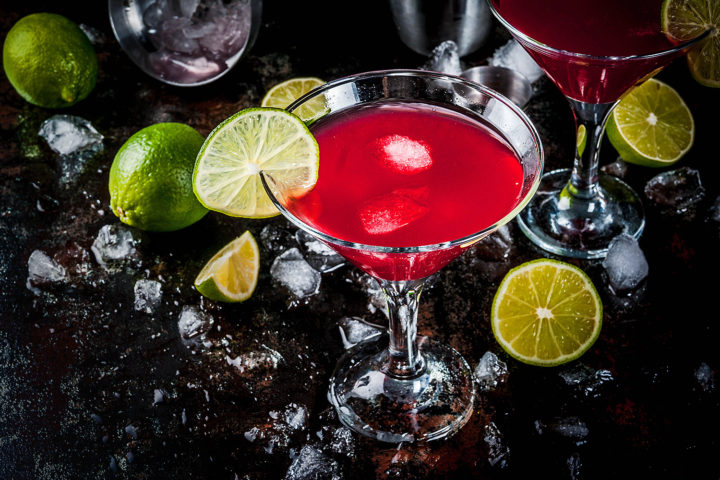 Red Cosmopolitan cocktail with lemon vodka, lime and cranberry juice on dark background