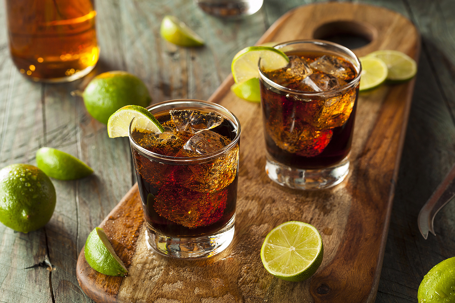 Cuba Libre cocktails from a wooden board garnished with limes