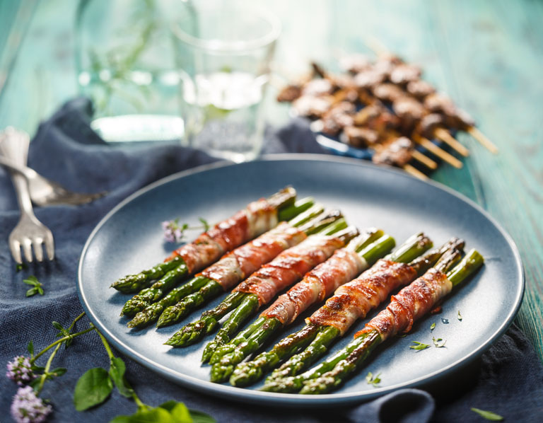 Green asparagus wrapped in bacon on a large plate