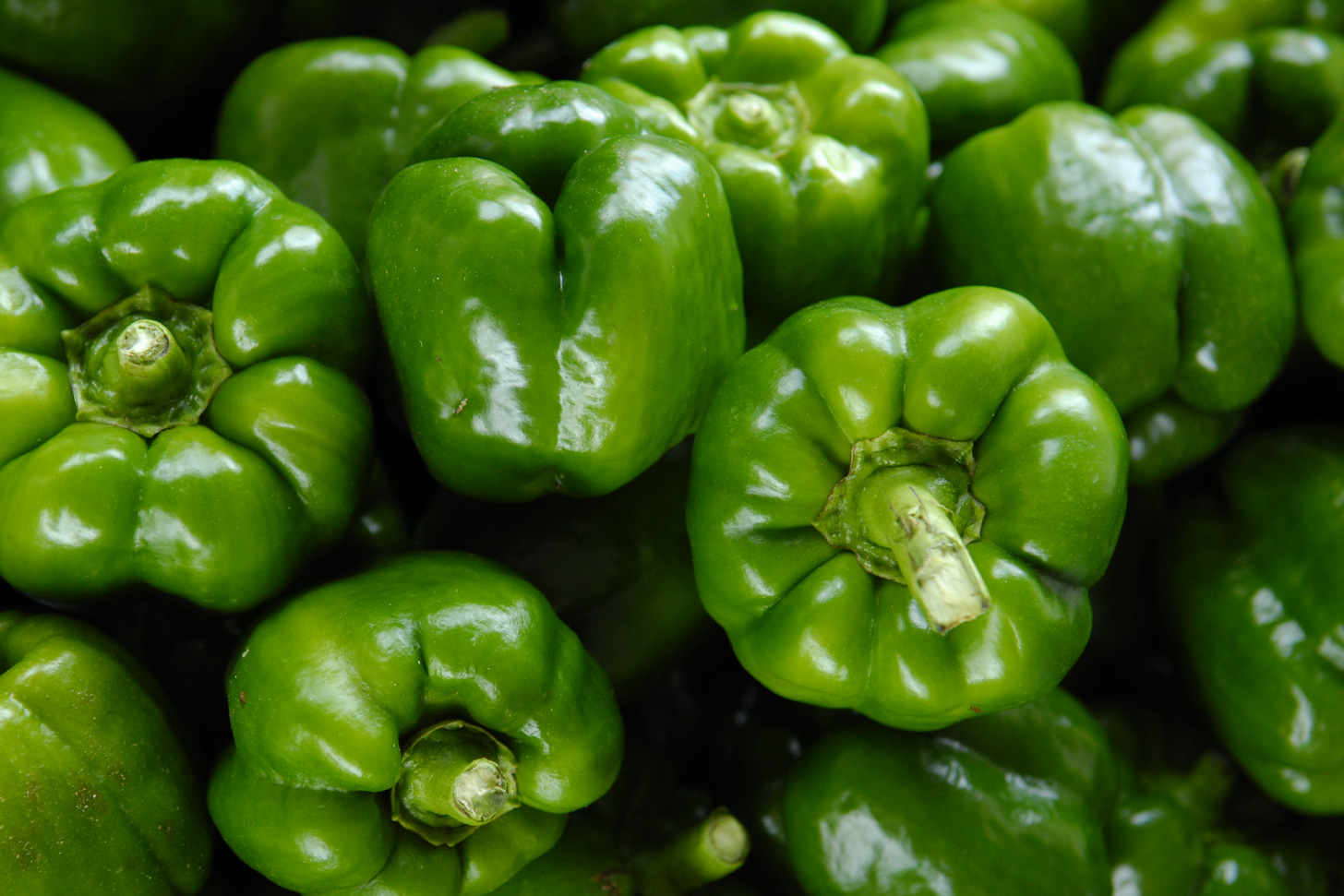 Several green peppers are lying in a pile.