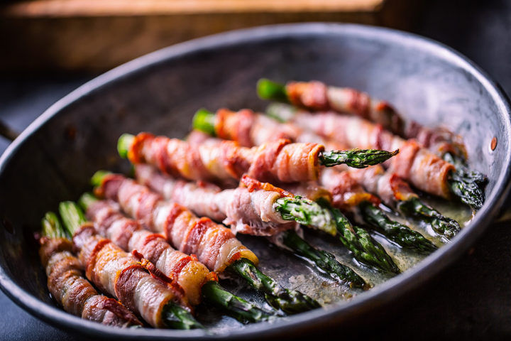 Gebratener grüner Spargel mit Edelschinken in einer Pfanne gebraten