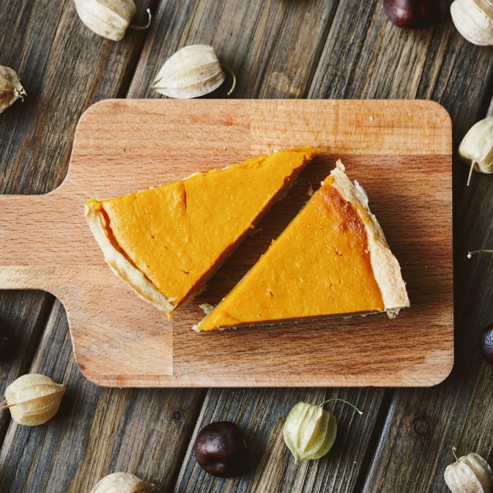 Zwei Stücke Kürbiskuchen auf einem kleinen Holzbrett serviert