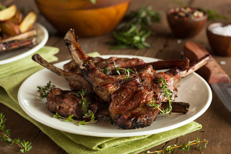 Roasted lamb chops on a plate decorated with thyme.