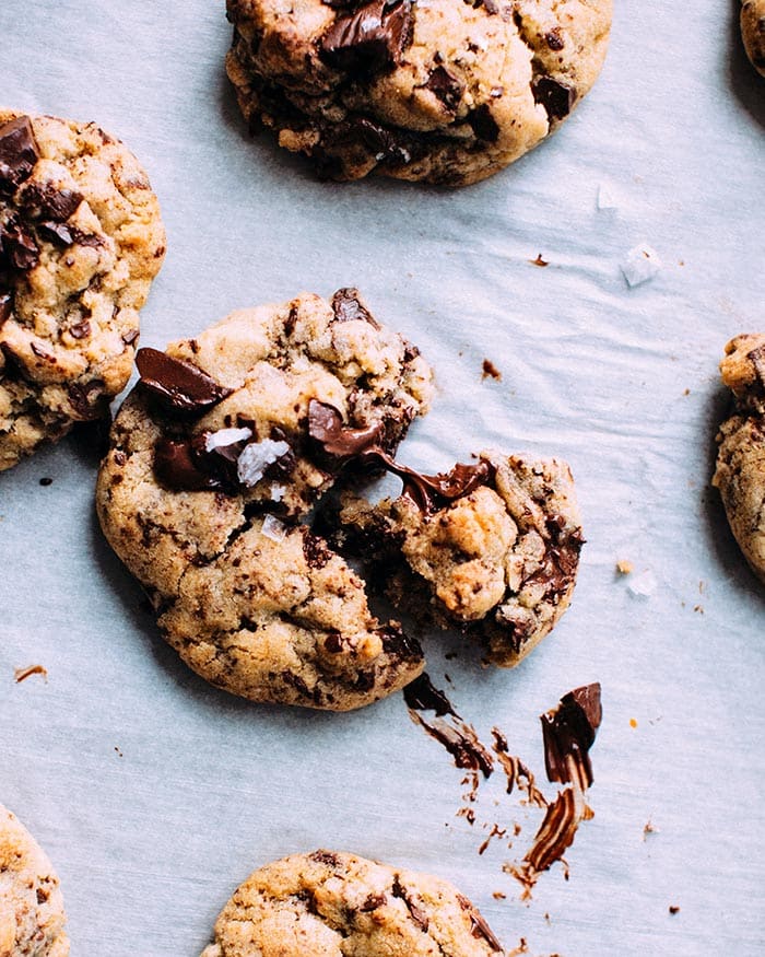 Chocolate chip cookies lying on a white baking paper with liquid chocolate center