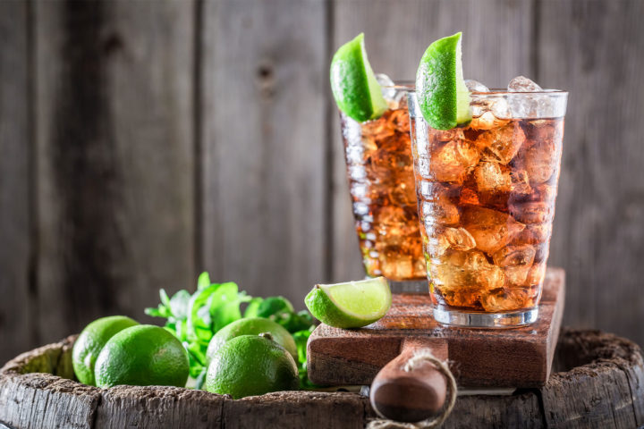 Long Island Ice Tea Cocktails mit Limetten auf einem Holzbrett