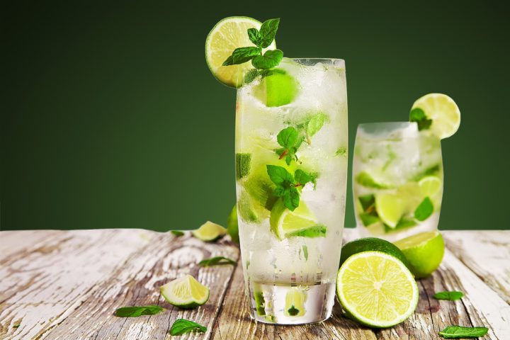 Mojito mit Limetten, Minze und Havanna Rum vor grünem Hintergrund