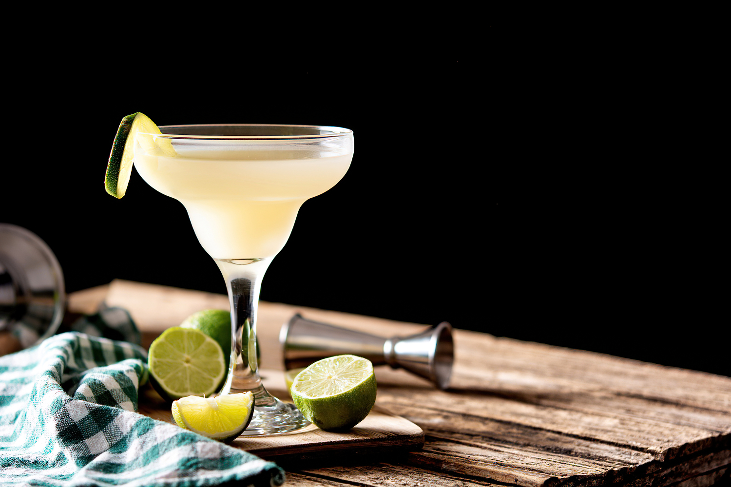 Original Daiquiri cocktail with white rum, lime juice and cane sugar syrup on a wooden board garnished with limes