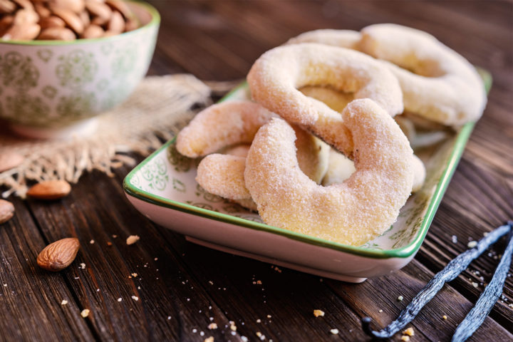 Perfekte Vanillekipferl mit Vanille und Mandeln in einem Schälchen auf Holztisch