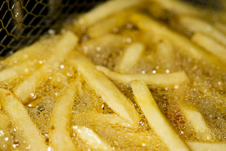 Pommes werden in einer heißen Fritteuse knusprig frittiert