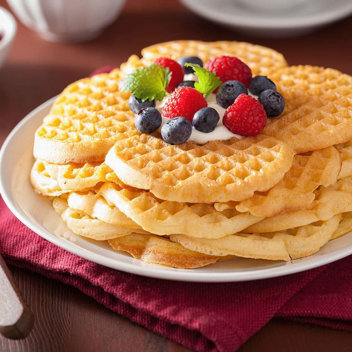 Leckere Waffeln mit Sahne und beerenfrüchten auf einem weißen Teller