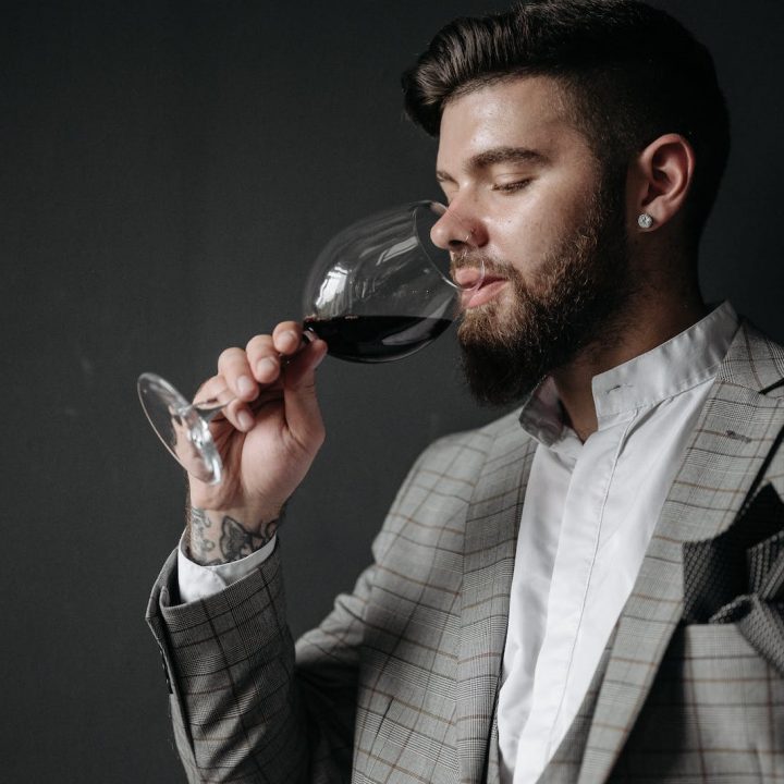 Mann im grauen Anzug hält ein Weinglas